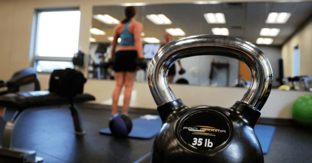 woman in a weight room exercising in front a mirror woman in a weight room exercising in front a mirror