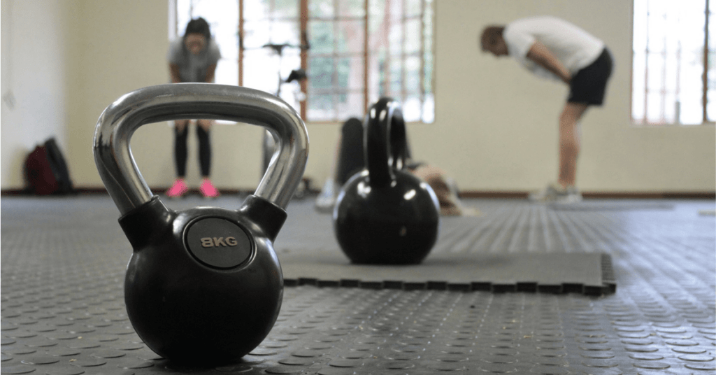 two kettle bells in a gym with people in the background two kettle bells in a gym with people in the background