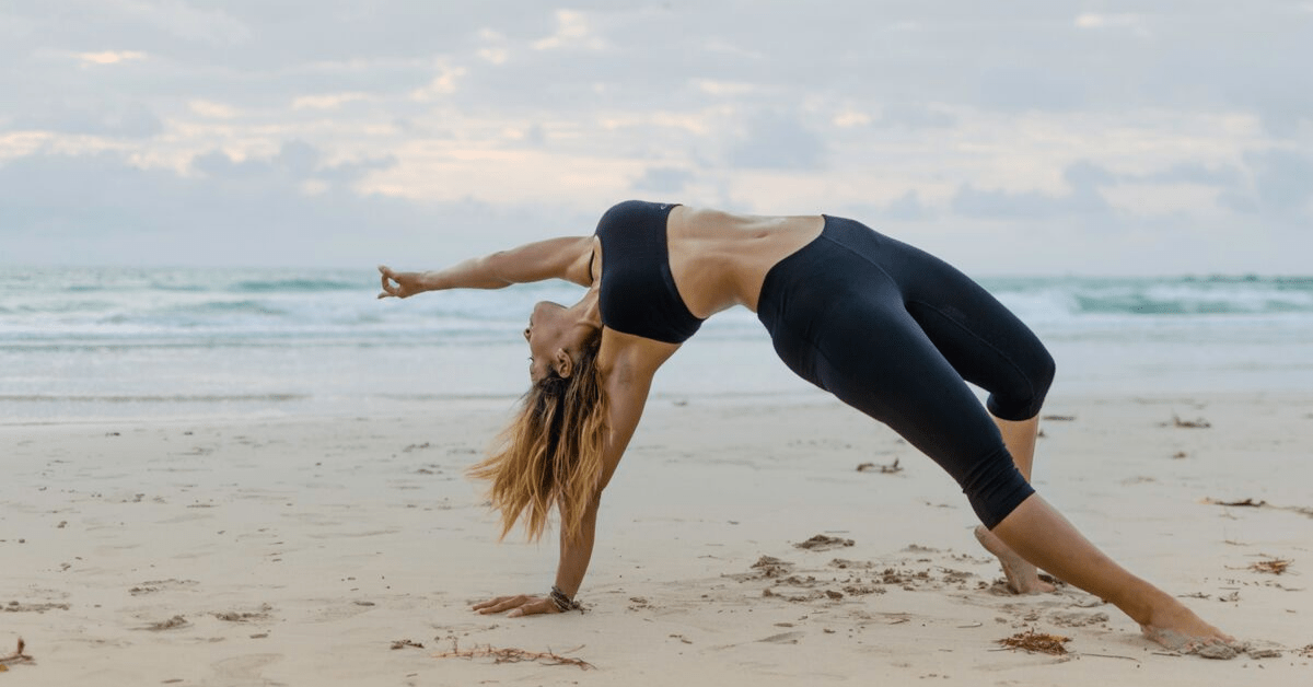 woman performing yoga pose on a beach